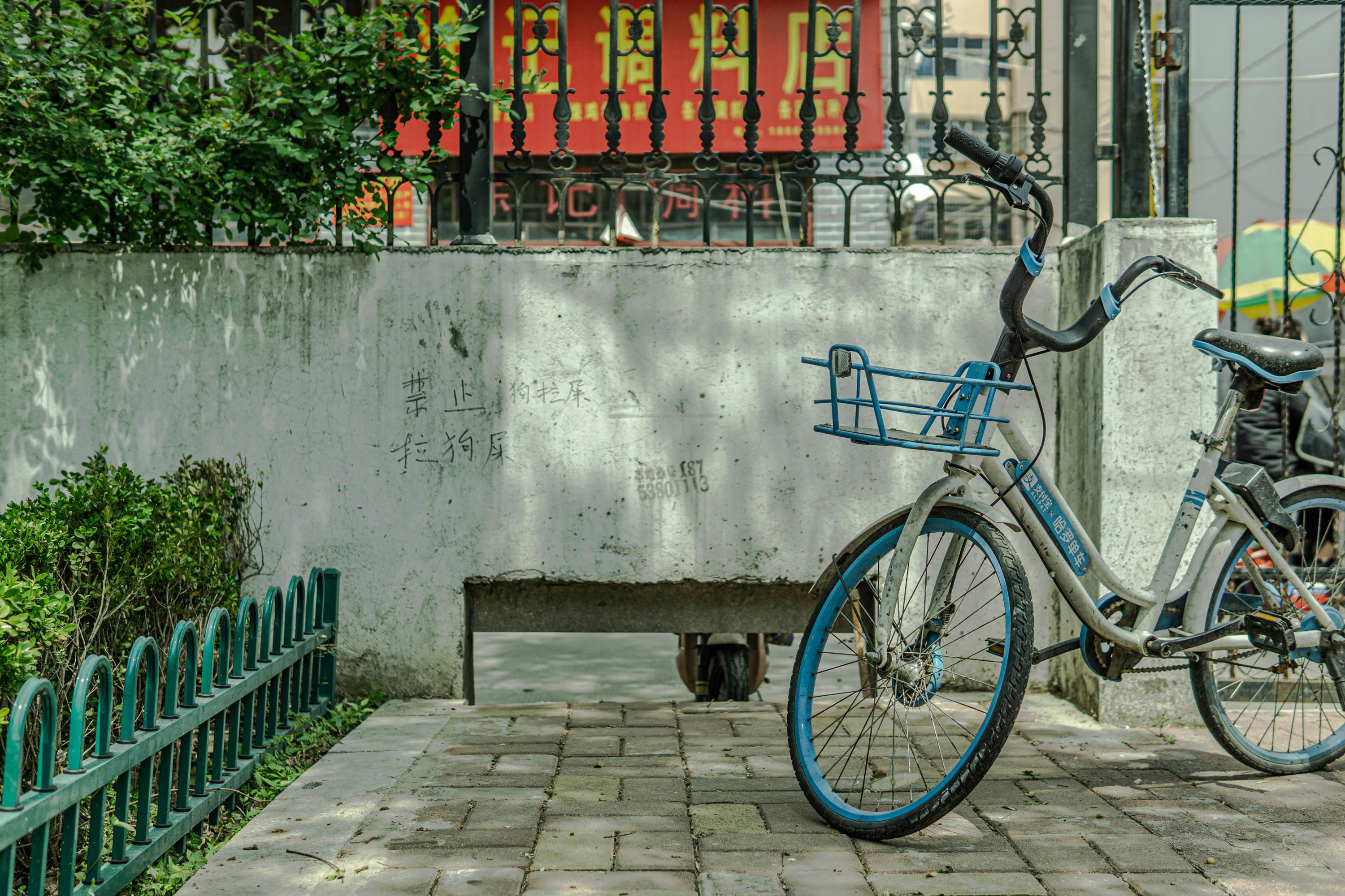 A blue bicycle parked next to a green fence
